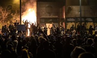 A group of people outside the burning Third Precinct building