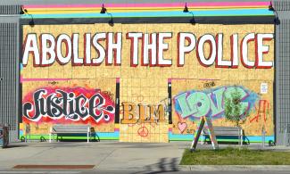 "Abolish the Police" grafitti on a boarded-up storefront