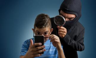 Masked person looking at another person's phone over their shoulder