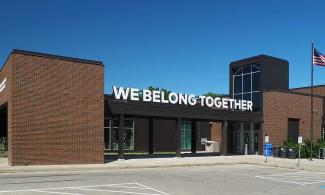 Photo of the Arlington Hills Library, with a large sign that reads "We Belong Together"
