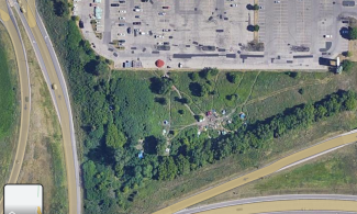 An overhead satellite image of a large parking lot, with the tents of Quarry Encampment to the South (at the bottom of the image, below the parking lot and above 35W) and The Home Depot and Cub buildings labeled to the North, beneath Great Northern Greenway / NE 18th Ave.